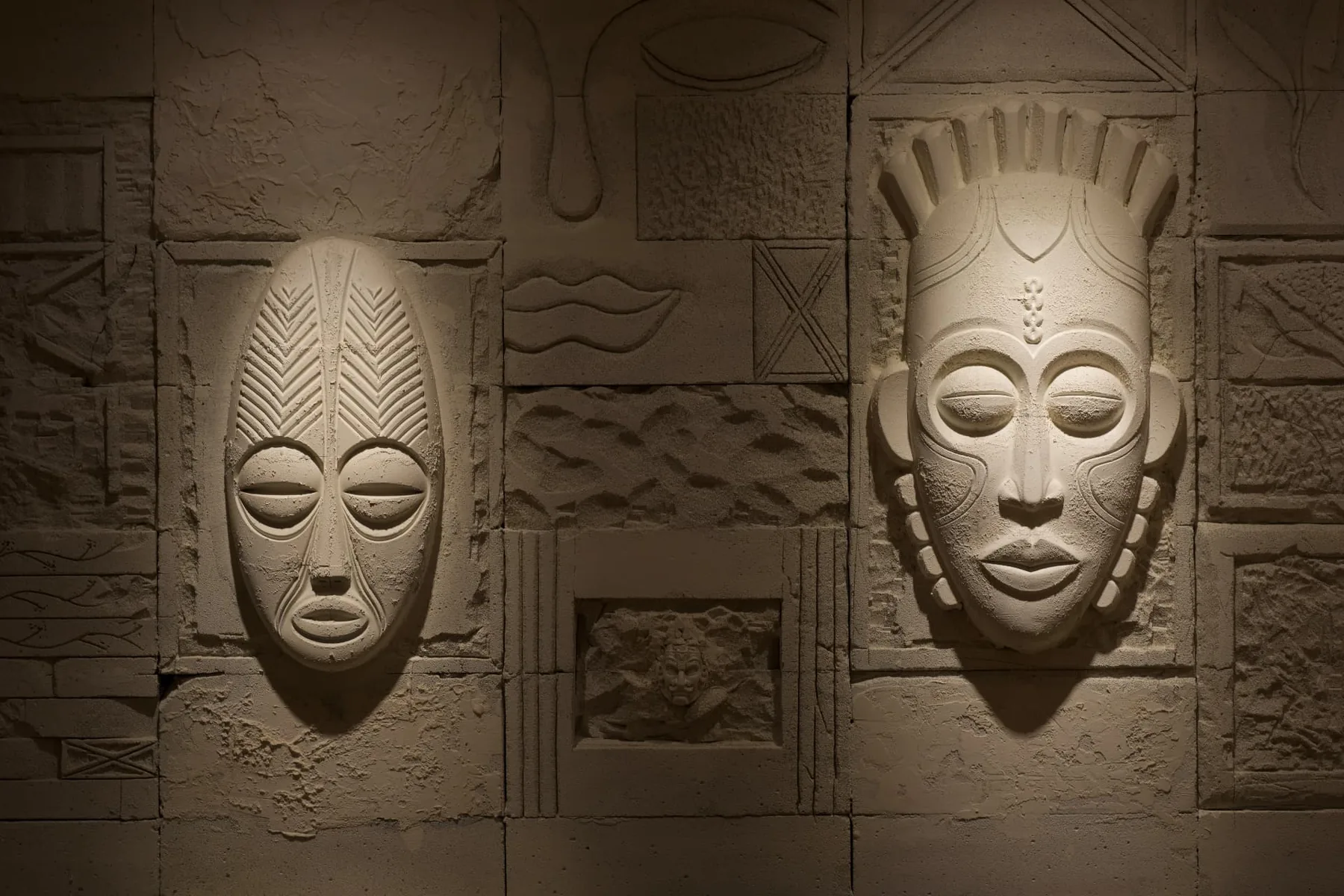 NEXA Atelier duvarında el işçiliği taş kabartma maske ve geometrik rölyef motifler